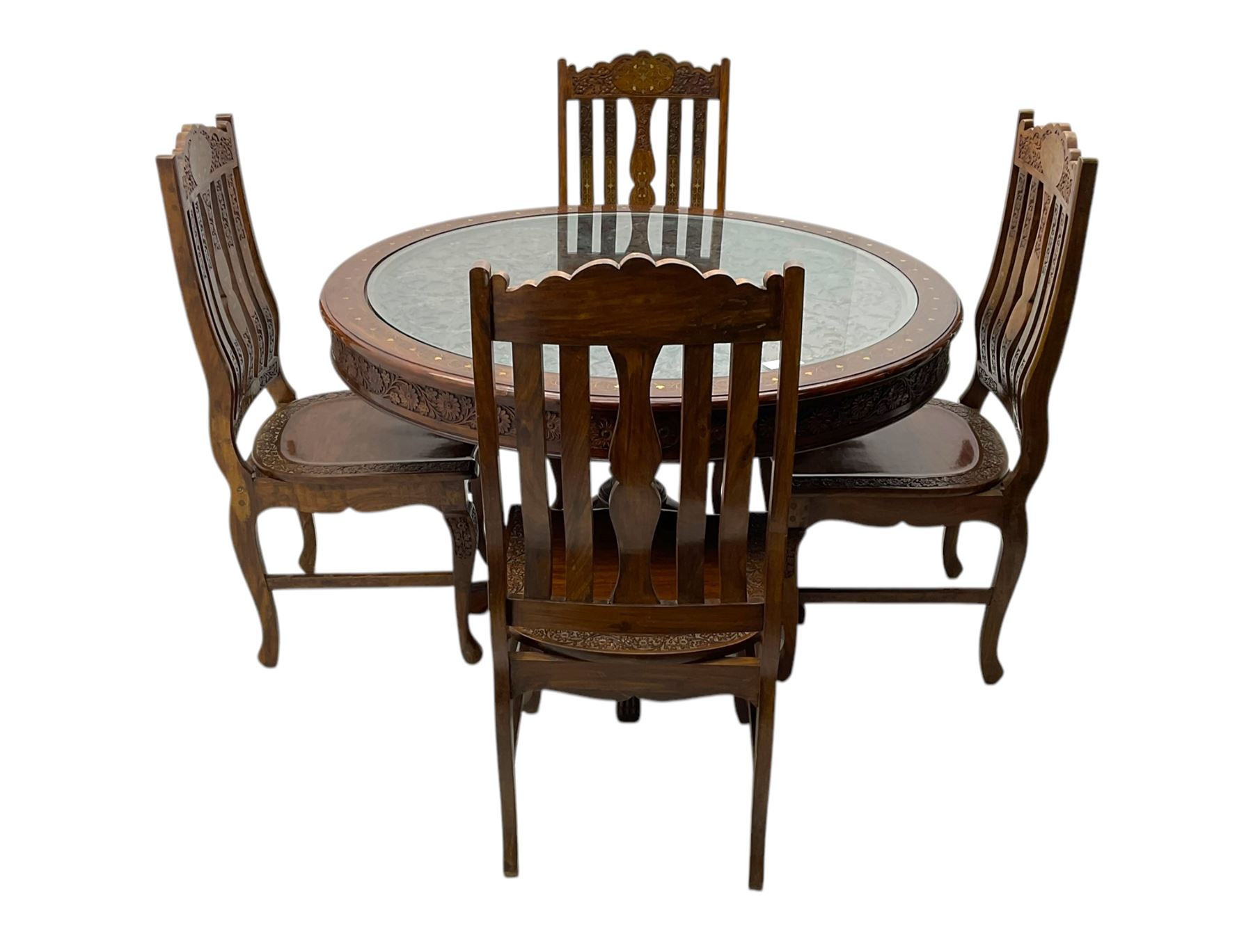 Pakistan carved hardwood brass inlaid circular dining table, and four rail back chairs with saddle seats