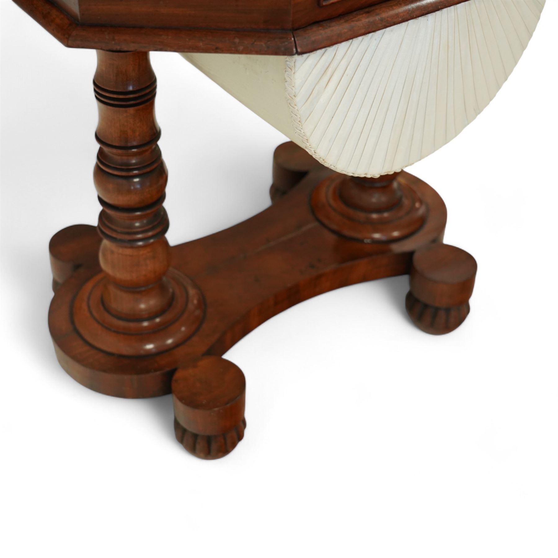 William IV mahogany work table, the octagonal top with ebony line inlay and dentil moulded edge, fitted with four small drawers to the frieze, above a silk-pleated sliding work basket, all raised on a turned column supports and shaped platform base with rounded feet, circa 1835