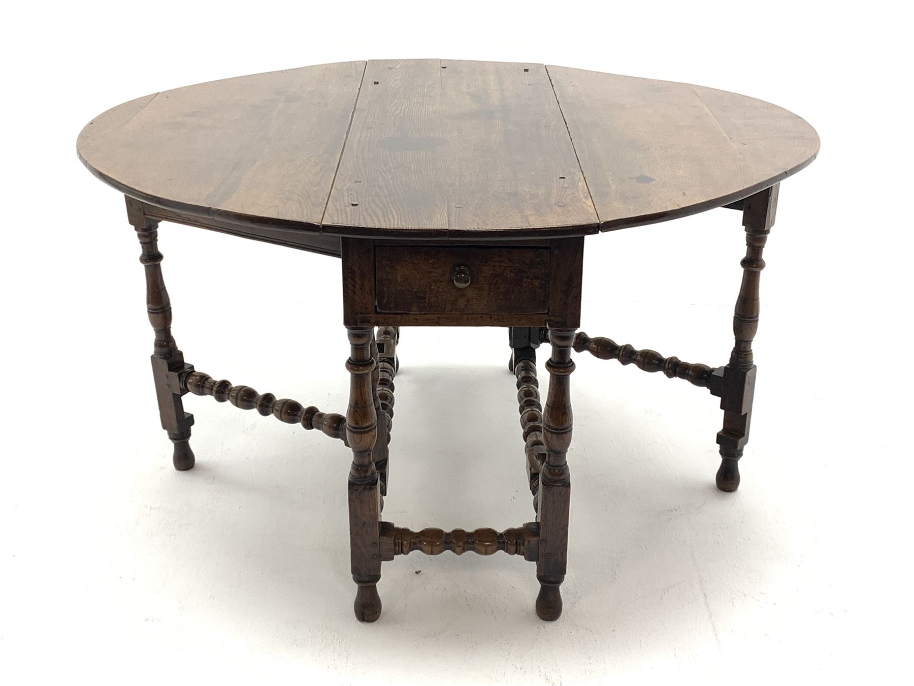 Late 17th century William & Mary oak drop leaf dining table, oval drop leaf top, single drawer to one end, gate action base, turned supports joined by bobbin turned stretchers, 121cm x 135cm, H75cm (open)
