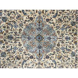 Central Persian Kashan hand-knotted carpet, ivory field with scrolling vines, palmettes, and rosettes around a cusped medallion with pendants and spandrels within a blue ground border of palmettes and flowerheads, 388cm x 300cm