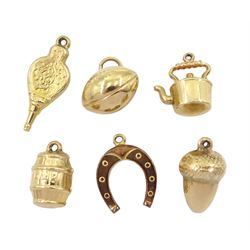 Six 9ct gold charms including acorn, barrel, ruby ball, horseshoe and kettle, all hallmarked