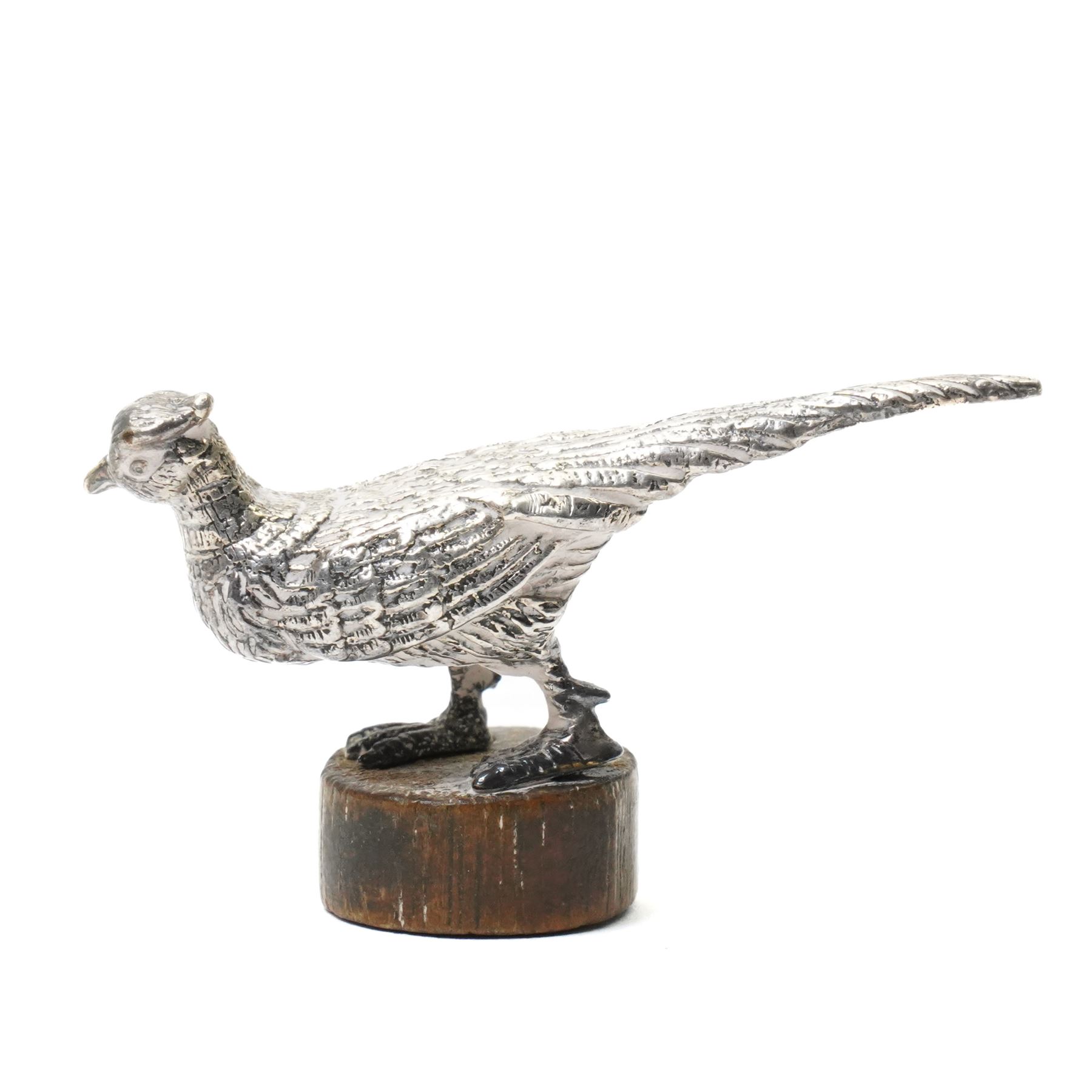 Silver model of a bird perched on a branch and with wooden base by Goldsmiths and Silversmiths Co. H5cm, small silver model of a pheasant on wooden base H2.5cm and a silver miniature model of a dog in a basket marked 925 and indistinct maker's mark L3.5cm (3)