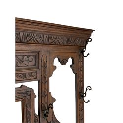 Victorian heavily carved oak hall-stand, moulded cornice with foliate carved decoration over bevelled mirror back, drop centre with hinged box seat flanked by stick or umbrella stands, scrolls and foliate carved decoration
