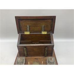 Edwardian oak and brass mounted desk stand, the brass pen rest over vacant brass cartouche, flanked two glass inkwells (lacking covers), before a stationary box, the hinged sloped lid with conforming vacant cartouche opening to reveal a fitted interior, H21.5cm L31.5cm D24cm