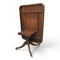 Regency mahogany tilt-top dining table, crossbanded rounded rectangular top, raised on a splayed base, terminating in brass castors