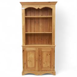 Contemporary pine kitchen dresser, moulded cornice over open plate rack with shaped frieze and two fixed shelves, enclosed lower section with panelled twin doors and shaped plinth base