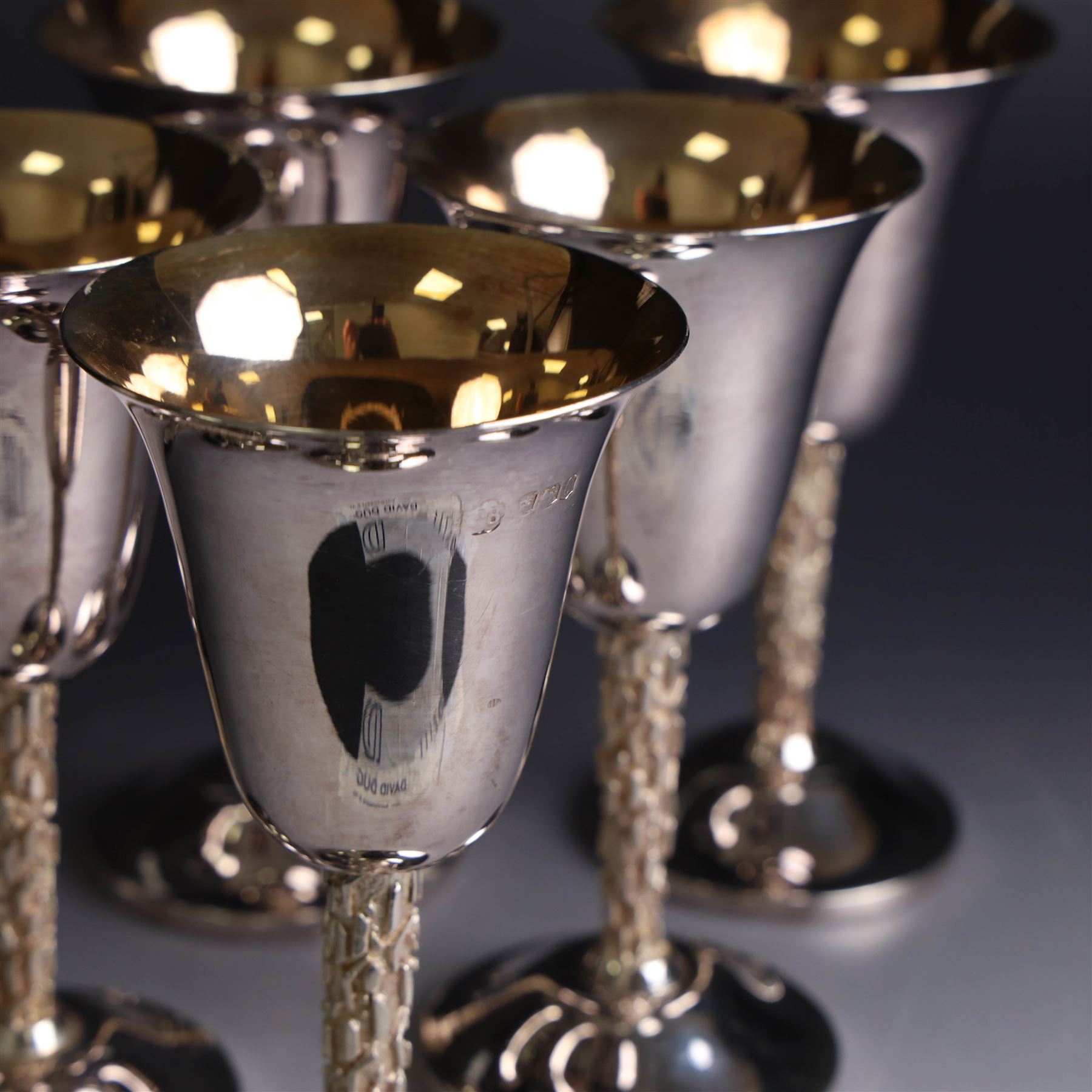 Eight silver goblets, comprising set of six, each plain fluted bowl with gilt interior, upon bark effect stem and domed circular foot, and a pair of very similar examples boxed with large hallmarks to bowls, hallmarked Pinder Brothers, Sheffield 1970 and Sheffield 1976, H14cm