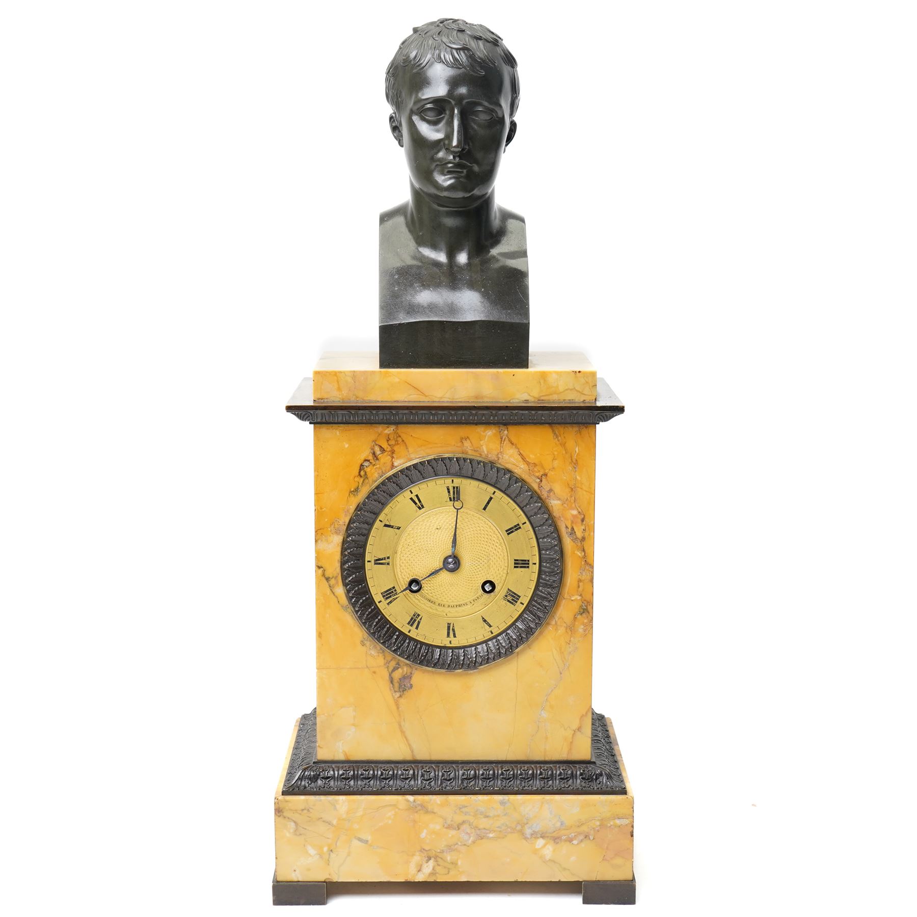 French-First quarter 19th century 8-day sienna marble and bronze-mounted mantel clock of rectangular architectural form, with patinated foliate guilloche pattern cast bronze mounts  in richly figured sienna marble, surmounted a by a classical patinated bronze bust of Napoleon Bonaparte, above a gilt engine turned dial with Roman numerals and blued steel hands, with a twin train Parisian countwheel striking movement, striking the hours and half-hours on a bell, silk suspension with thumb-screw adjustment. With pendulum.