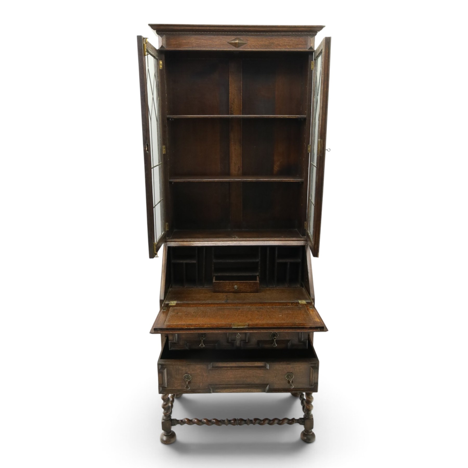 Early 20th century Jacobean Revival oak bureau-bookcase, astragal glazed doors enclosing two adjustable shelves, over geometric panelled fall-front enclosing fitted interior, over two drawers, raised on a spiral-turned base with barley-twist stretchers and compressed bun feet