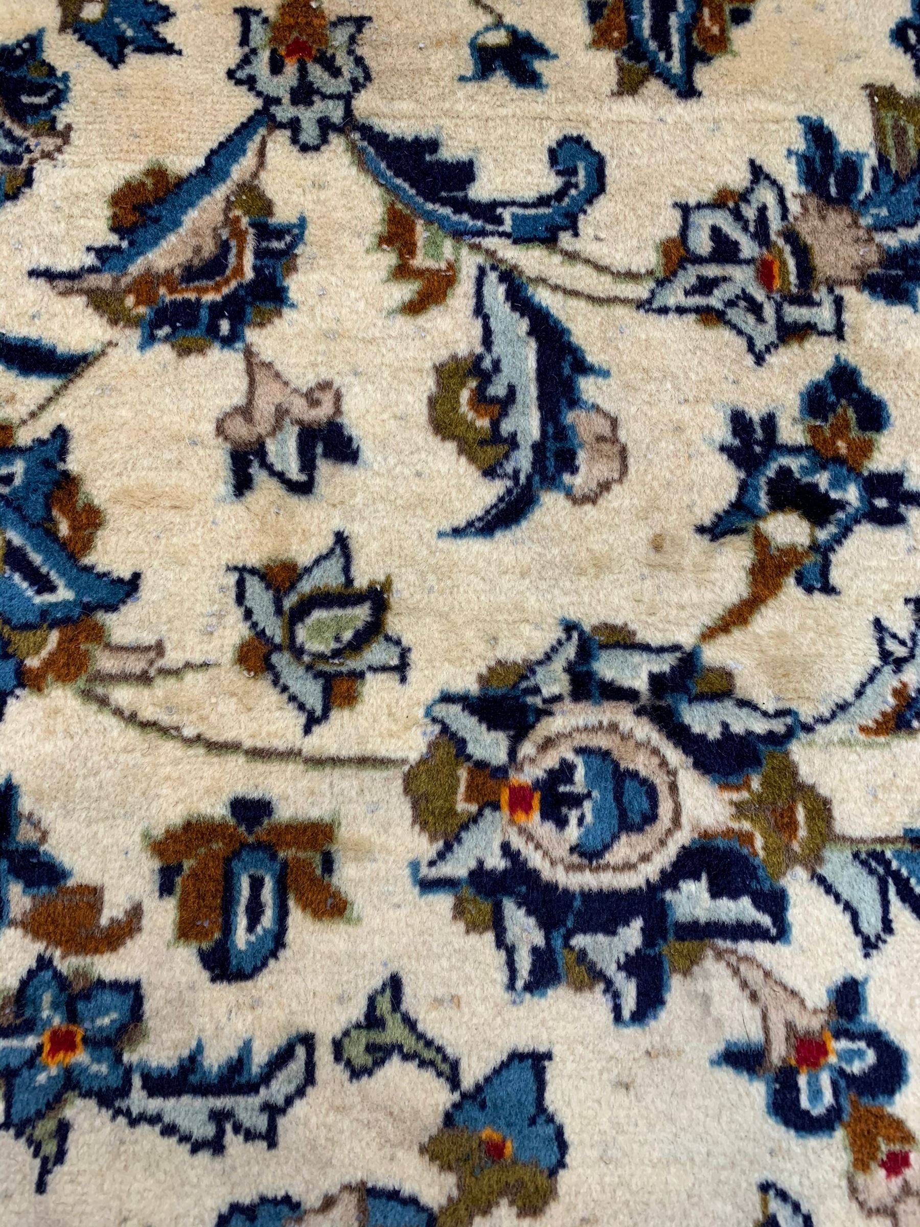 Persian Kashan ivory ground rug, the field decorated with stylised plant motifs and interlacing leafy branches, scrolling border decorated with further plant motifs, floral design guard bands  