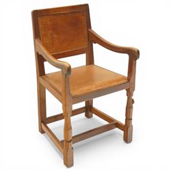 Mouseman - oak panel back carver armchair, lightly adzed panel back above a tan seat with brass studded trim, flanked by swept arms raised on octagonal front supports, with carved mouse signature, by the workshop of Robert Thompson of Kilburn