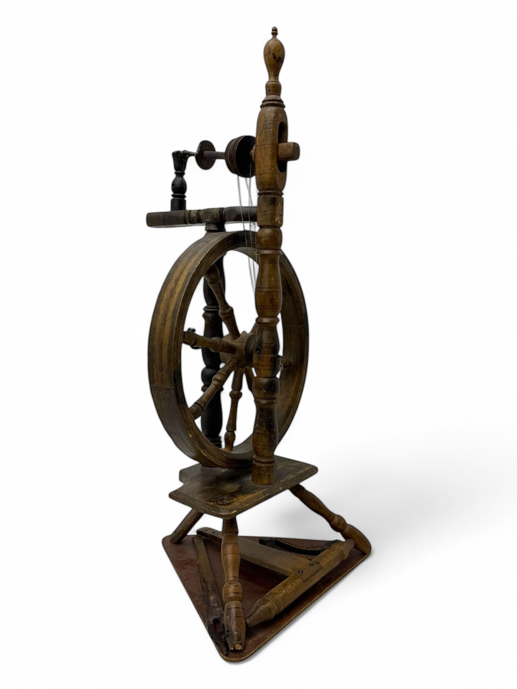 Late 19th century turned beech spinning wheel, upright form with single treadle, triangular base, and a flyer and bobbin assembly surmounted by a turned finial.