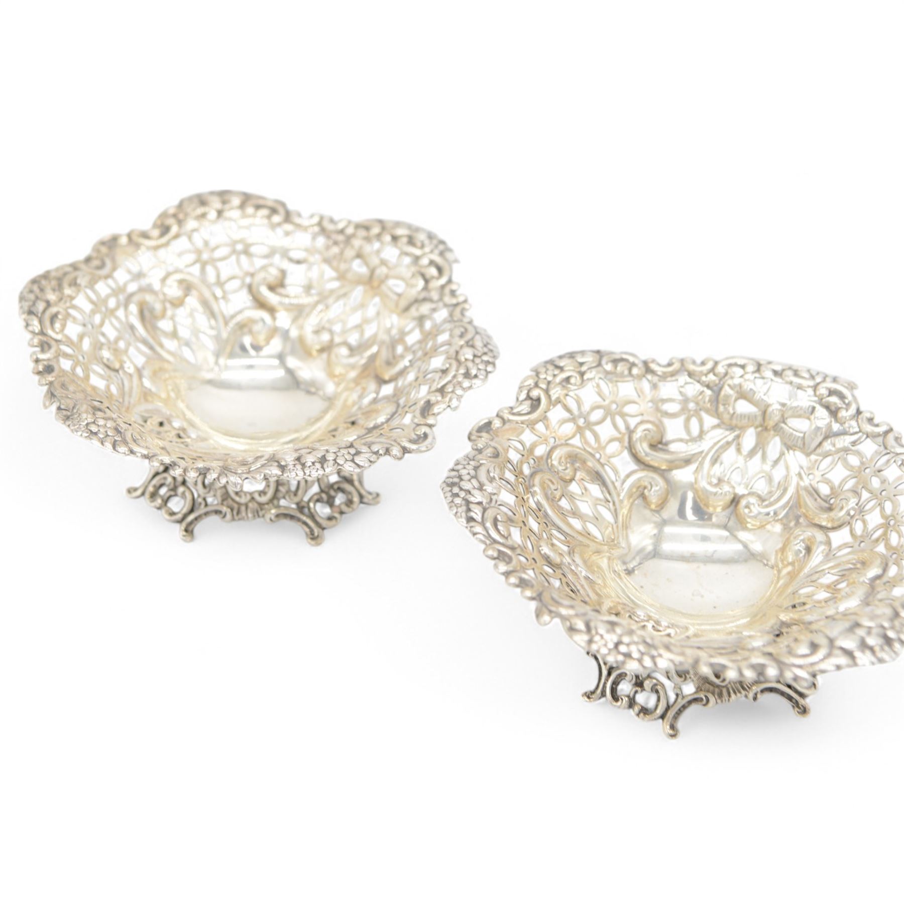 Pair of late Victorian silver bon bon dishes, of hexagonal form with embossed and pierced scrolling decoration, upon a circular pierced base, hallmarked Goldsmiths & Silversmiths Co, Birmingham 1893, W11cm, H4cm