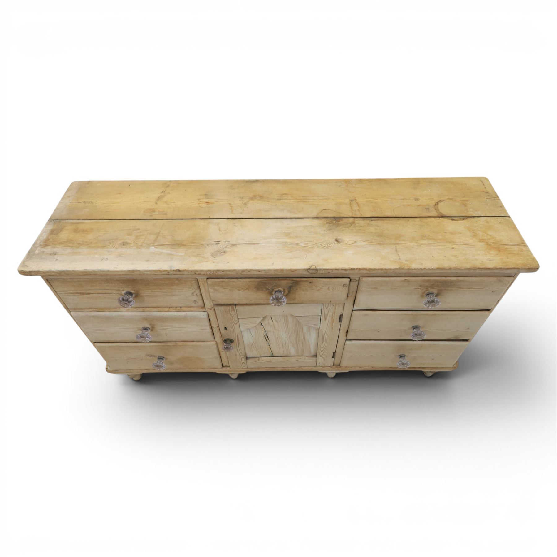 Victorian waxed pine farmhouse dresser, featuring seven drawers with central cupboard, moulded glass handles, raised on turned feet