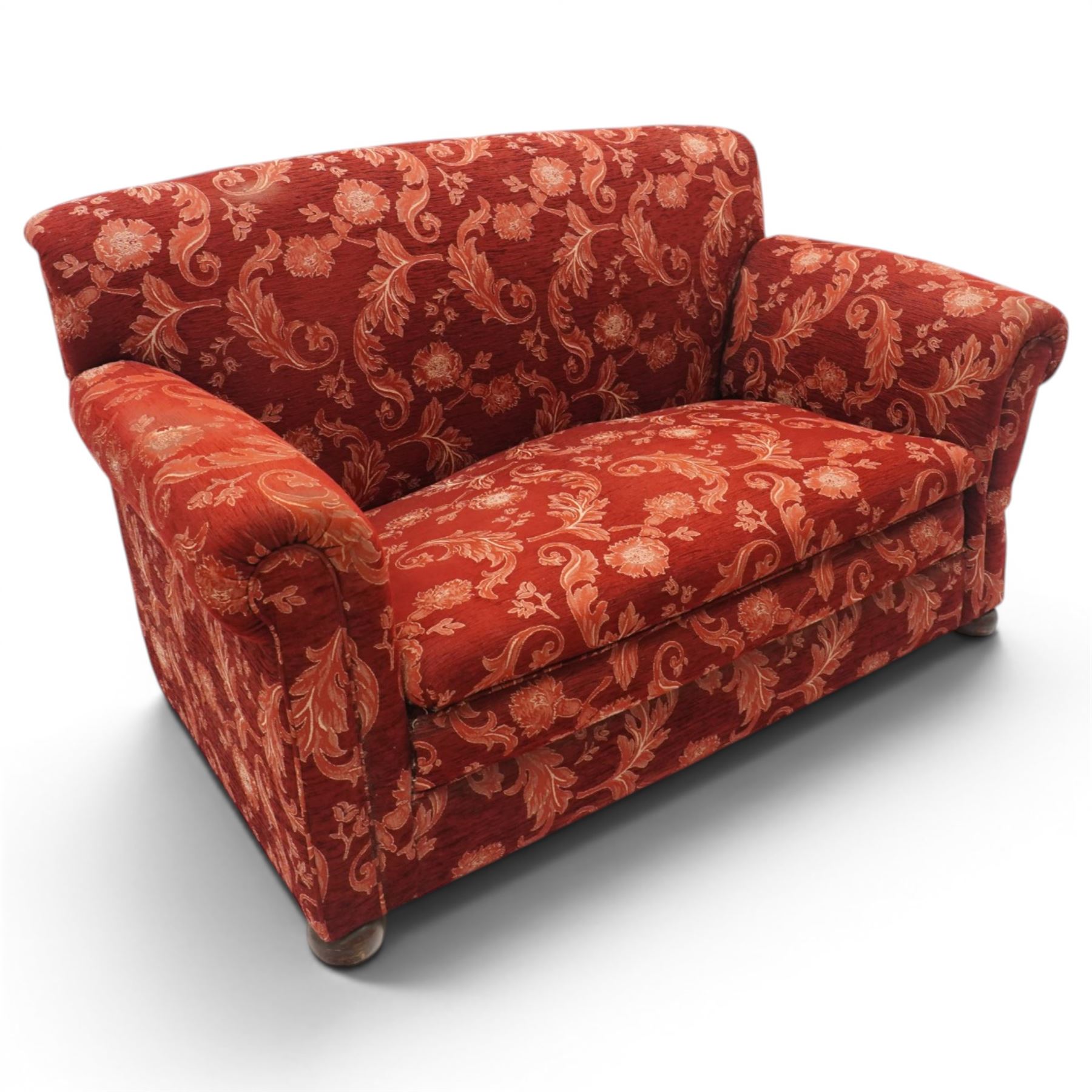 Edwardian hardwood framed petite two seat settee with single drop-arm, traditional shape with rolled arms, the drop-end with lever action adjustable height, the sprung back and seat upholstered in crimson foliate patterned fabric, on compressed bun feet