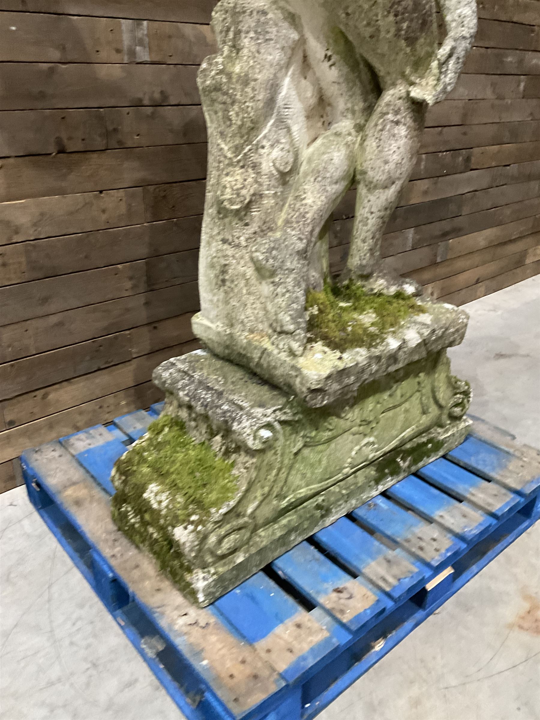 Life-size weathered cast stone Greek Discus Athlete, seated on rectangular slab raised on associated architectural plinth