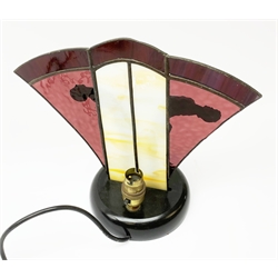 An Art Deco style table lamp, modelled in the form of two nude figures before a leaded purple and cream fan shaped glass shade, overall H26cm.