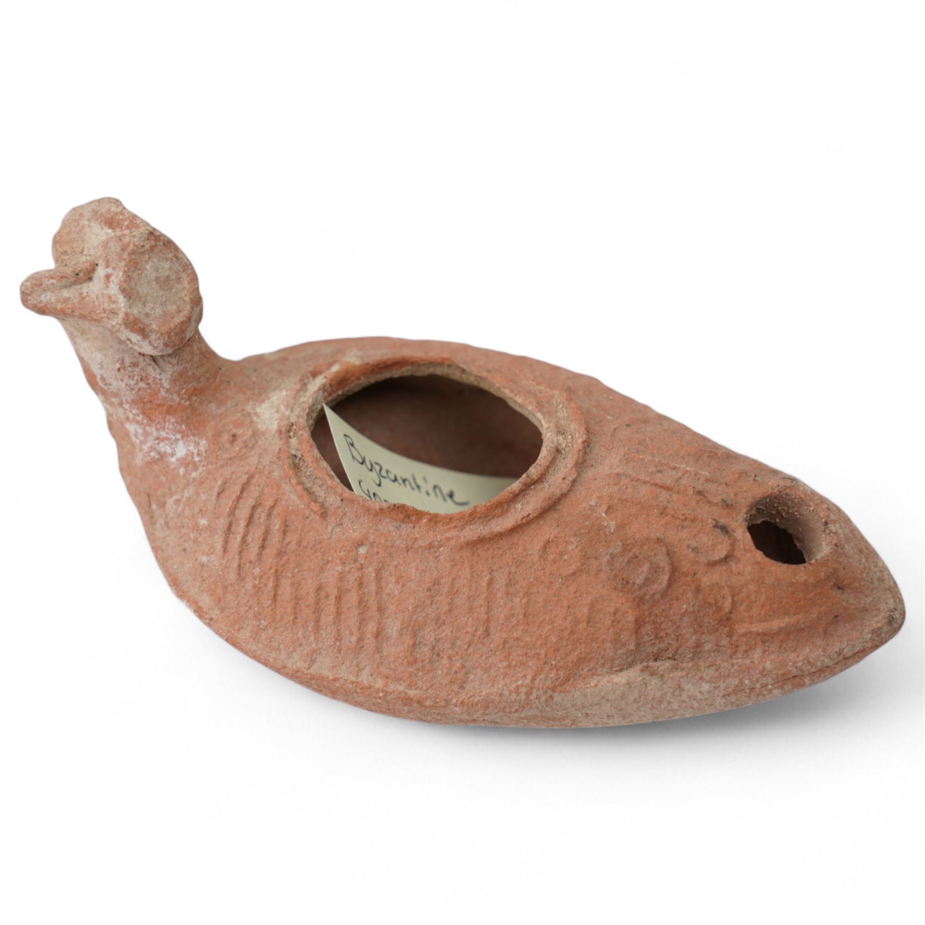 A group of four Byzantine terracotta oil lamps - Eastern Mediterranean, c.5th-7th century AD, comprising a group of mould-made slipper-form oil lamps, each with a rounded body, large central filling hole, and a short to elongated nozzle; including one with fine radiating linear decoration, and another preserving ancient use with traces of oil and wick residue within the burnished interior; together with a Crusader-period terracotta oil lamp (c.12th-13th century AD) of angular form with recessed panel decoration and a pierced handle moulded as a stylised animal head
Provenance: By the vendor’s repute, acquired/collected in the Middle East (Dead Sea area/Syria) in the 1960s