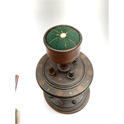 A 19th century turned oak and fruitwood bobbin stand, upon three turned feet supporting a stepped lower platform with spindles, leading to turned stem, further graduated platform with acorn finials and goblet shaped pin cushion, overall H36.5cm.