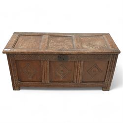 18th century oak coffer or blanket box, triple panel hinged lid over panelled front and sides, the front carved with scrolling foliate motifs and lozenges, moulded frame with chip carved decoration on stile supports 