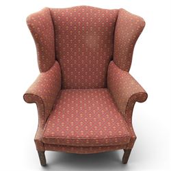 Georgian design wingback armchairs, the high backs flanked by shaped wings over padded scroll arms, upholstered in burgundy and gilt fleur-de-lys patterned fabric, loose cushion seats, raised on square tapering front supports