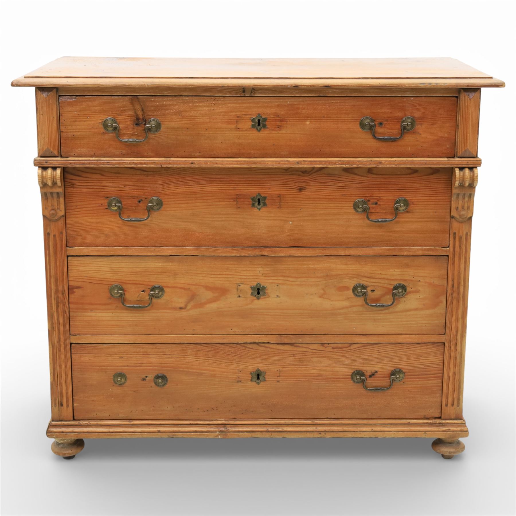 Late Victorian pine chest of drawers, the moulded top above four long drawers with brass drop handles and flower head escutcheons, flanked by pilasters, upon four turned compressed bun feet, 89cm x 103cm x 54cm
