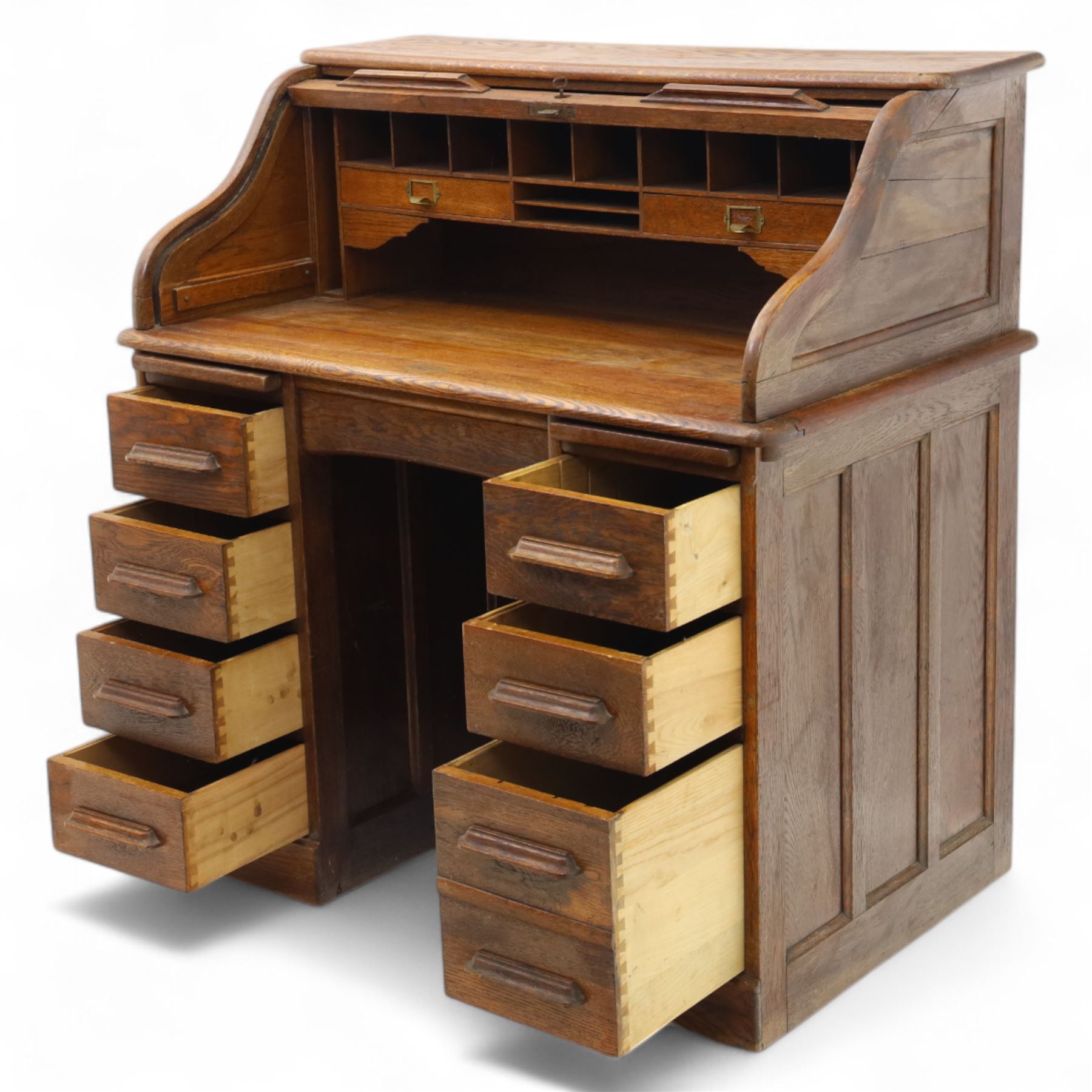 Early 20th-century oak roll-top desk with tambour shutter, enclosing a fitted interior of pigeon holes and small drawers, and pedestal base fitted with nine drawers with moulded handles, raised on plinth base 
