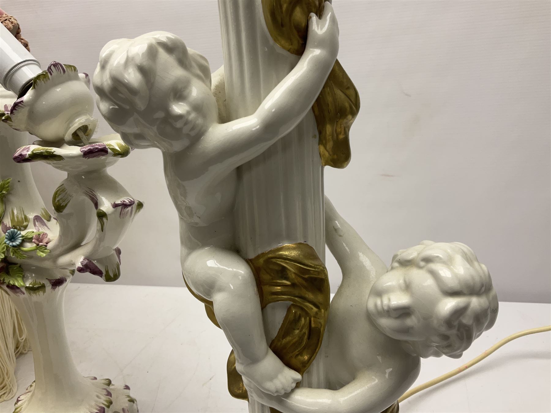 Jaffe Rose figural ceramic table lamp, modelled as two putti climbing a column with gilded cloth, together with a Capodimonte floral two light table lamp and a collection of lamp shades