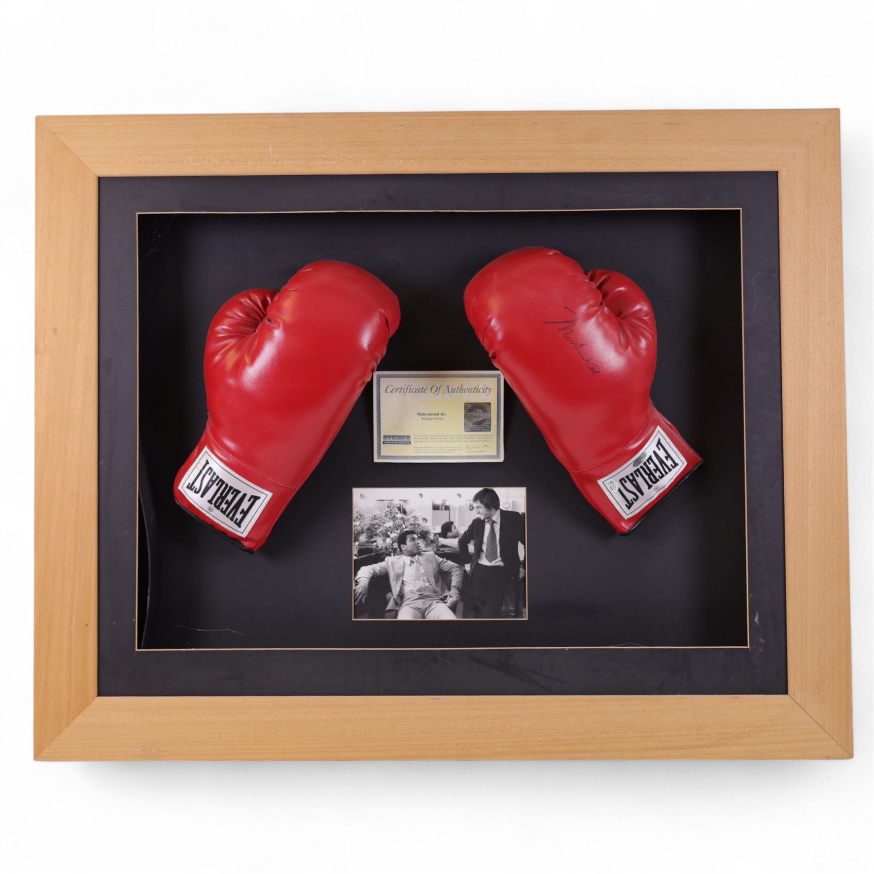 Large framed display containing two Everlast boxing gloves, one signed Mohammed Ali, displayed in frame with black and white photograph of Mohammed Ali speaking with Michael Parkinson, the signed glove has a Steiner authenticity hologram affixed and comes with certificate of authenticity from Steiner Sporting Memorabilia, frame H73cm