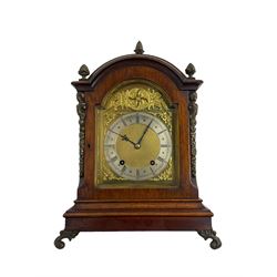 Eearly 20th century German mahogany cased bracket clock with an eight-day going barrel movement striking the quarters on two gongs and hours on one, in a break arch case surmounted with brass pineapple finials, silk backed pierced brass sound frets, canted brass caryatids and raised on outward scrolled feet, conforming break arch dial with a silver chapter ring, spandrels, steel fleur di Lis hands and matted dial centre. With key and pendulum.