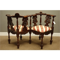  Heavily carved reproduction mahogany love seat, with masks, shells and foliage decoration, drop in seats upholstered in striped fabric, W130cm  