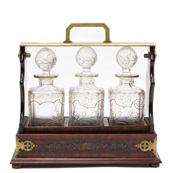 Amboyna three bottle tantalus, the cut glass spirit decanters decorated with raised naturalistic decoration heightened in gilt, with brass corner mounts and singular carrying handle, H32cm