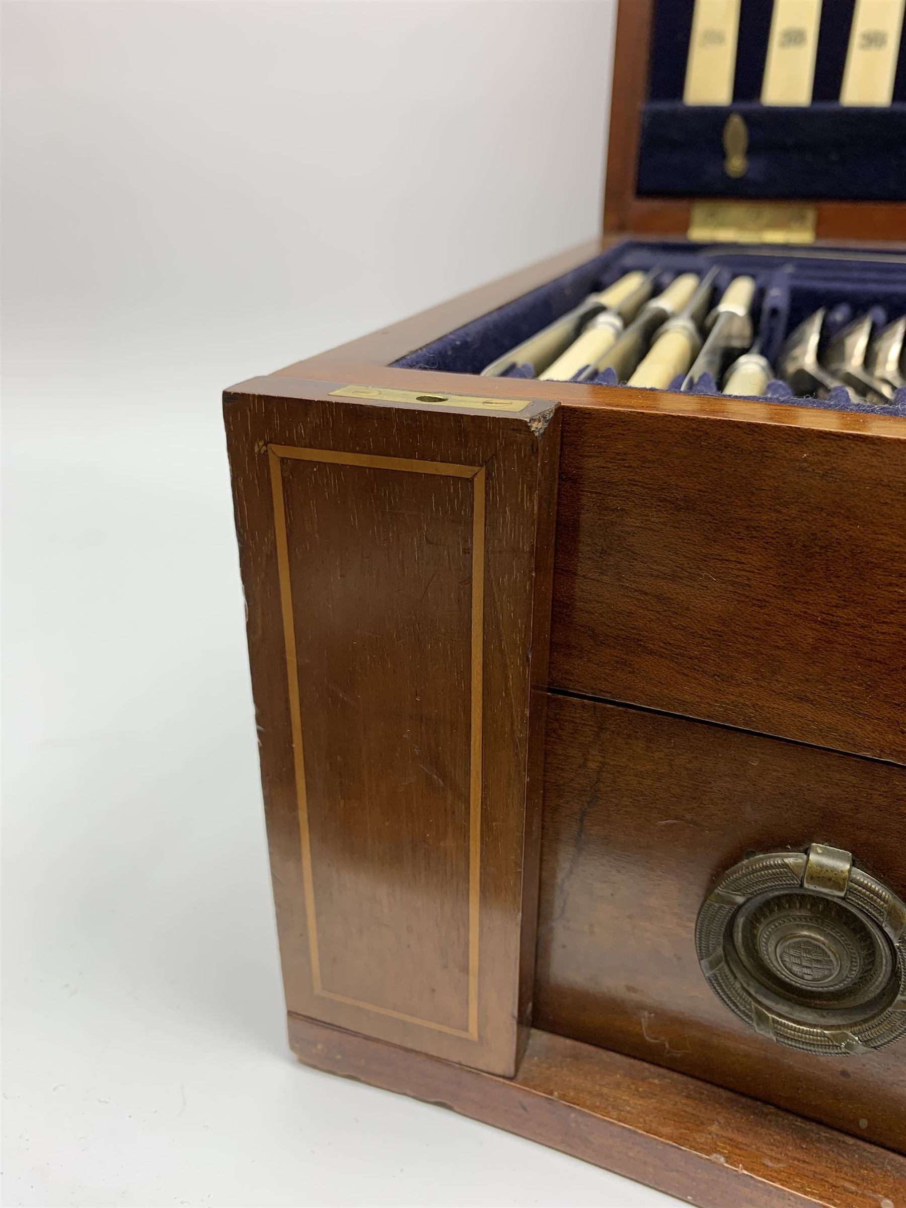 Late 19th/early 20th century composite canteen of silver flatware, contained within an early 20th century mahogany serpentine fronted case with twin drop carry handles, and hinged cover with boxwood stringing and central inlaid shell motif, above a single drawer with twin ring handles and Wellington style locking system, the cover and drawer opening to reveal plaque for Spink & Sons Ltd London, and fitted interior containing ivory handled knives, ivory handled carving set, and silver Hanoverian and Old English pattern cutlery, each with engraved monogram to terminal, hallmarked London, makers Spink & Son (John Marshall Spink), Goldsmiths & Silversmiths Co, and Chawner & Co (George William Adams), various dates ranging 1880-1923, gross weighable silver 92.59 ozt (2880 grams)