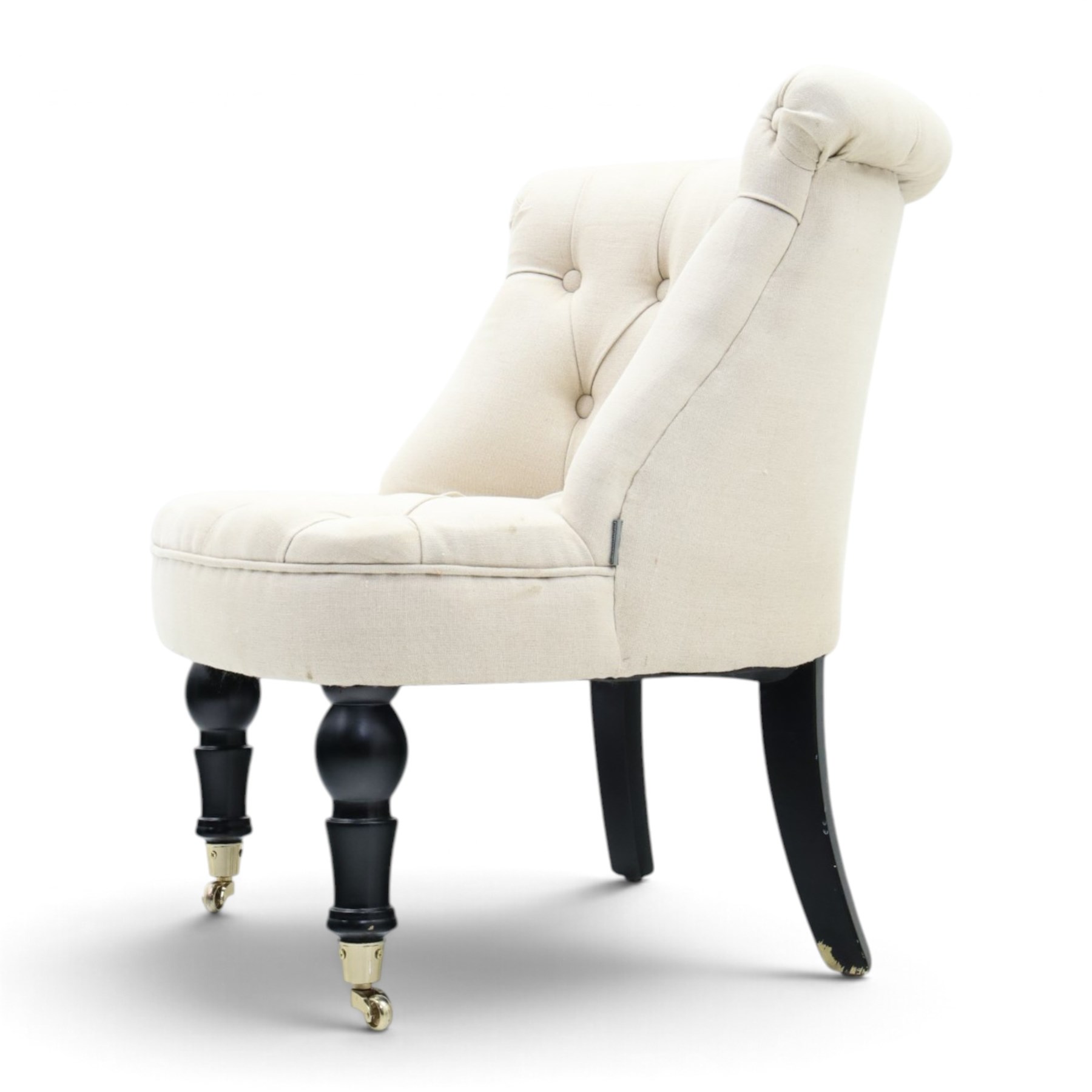 Victorian style upholstered tub chair, buttoned cream fabric back and seat with rolled sides, on ebonised turned front supports with brass castors and splayed rear supports