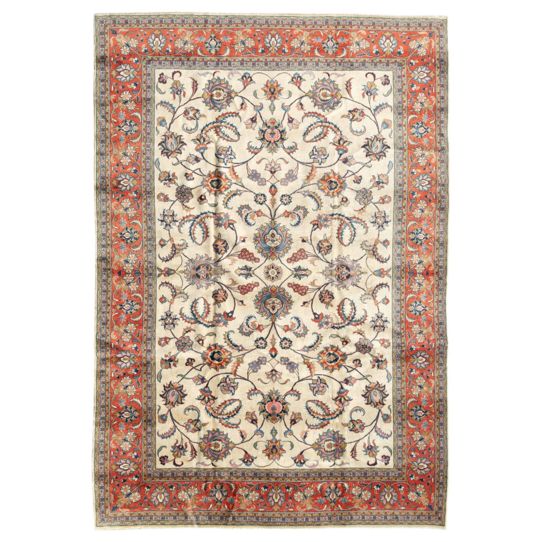 Persian Sarough carpet, ivory field with symmetrical arrangement of scrolling vines, palmettes and floral sprays in red, blue and green, enclosed by a broad red main border with repeating floral motifs, originating from the Arak region of Iran