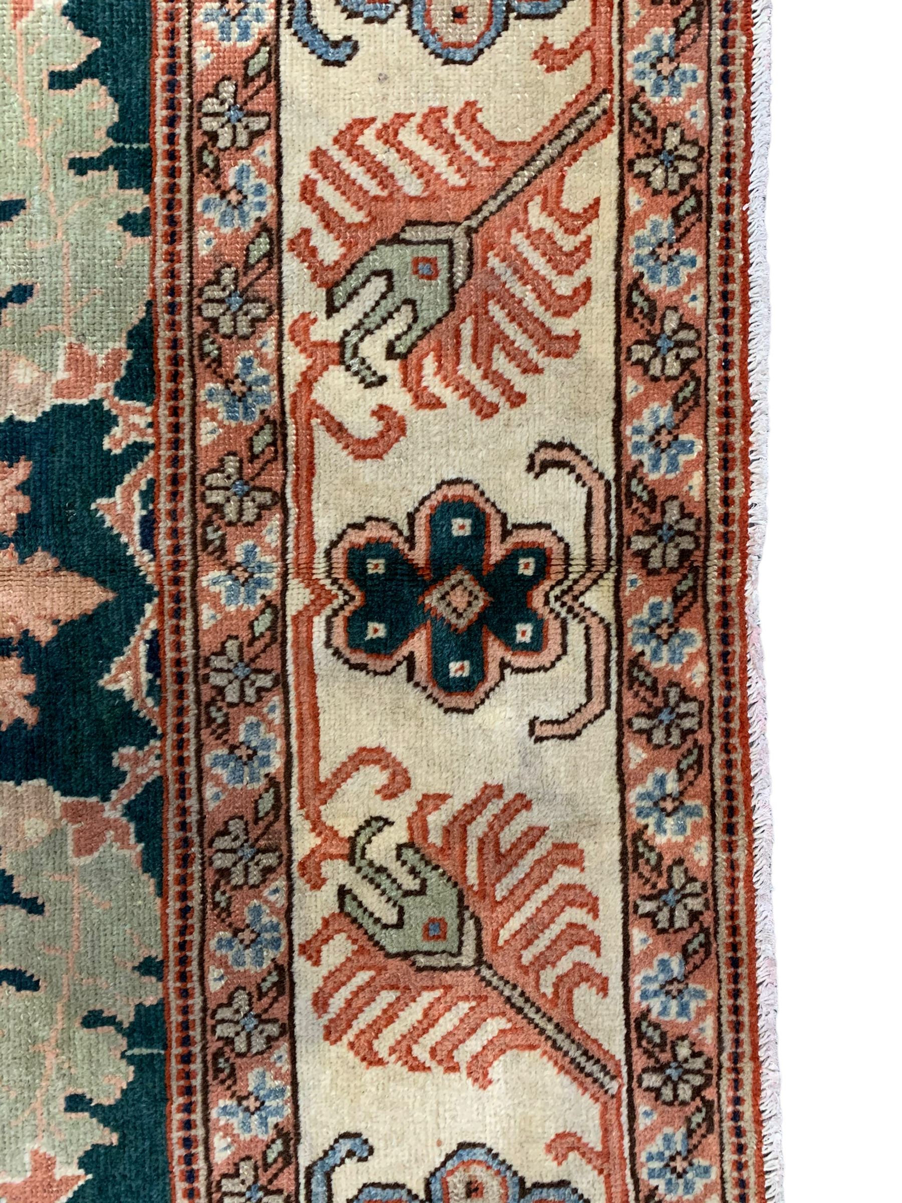 Persian emerald green ground rug, the field decorated with large stylised plant motifs, ivory ground border with repeating leaf motifs, the guards decorated with trailing branch and flowerhead motifs