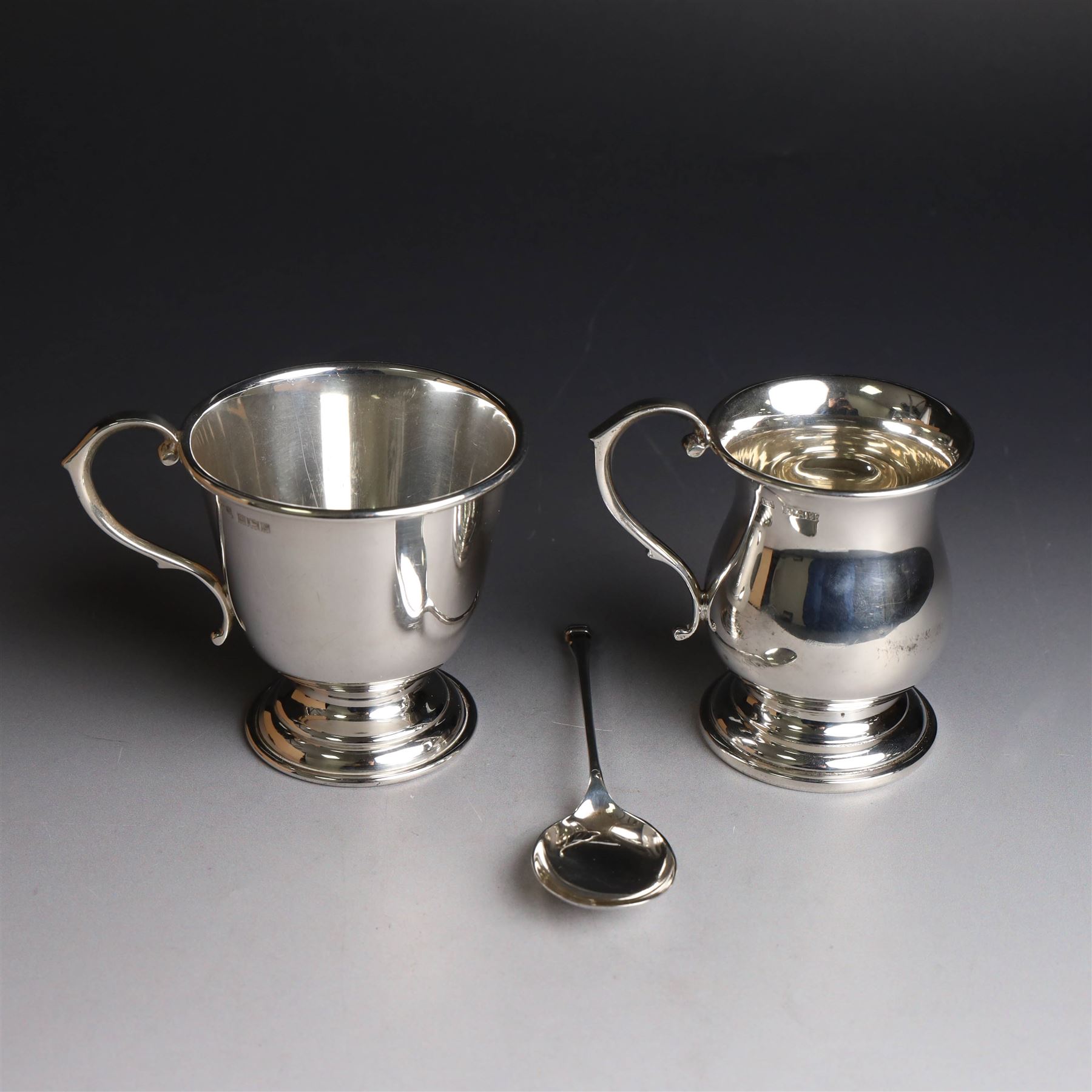 Two late 20th century silver christening mugs, each of plain form with no engraving, together with a small seal top spoon, all hallmarked 
