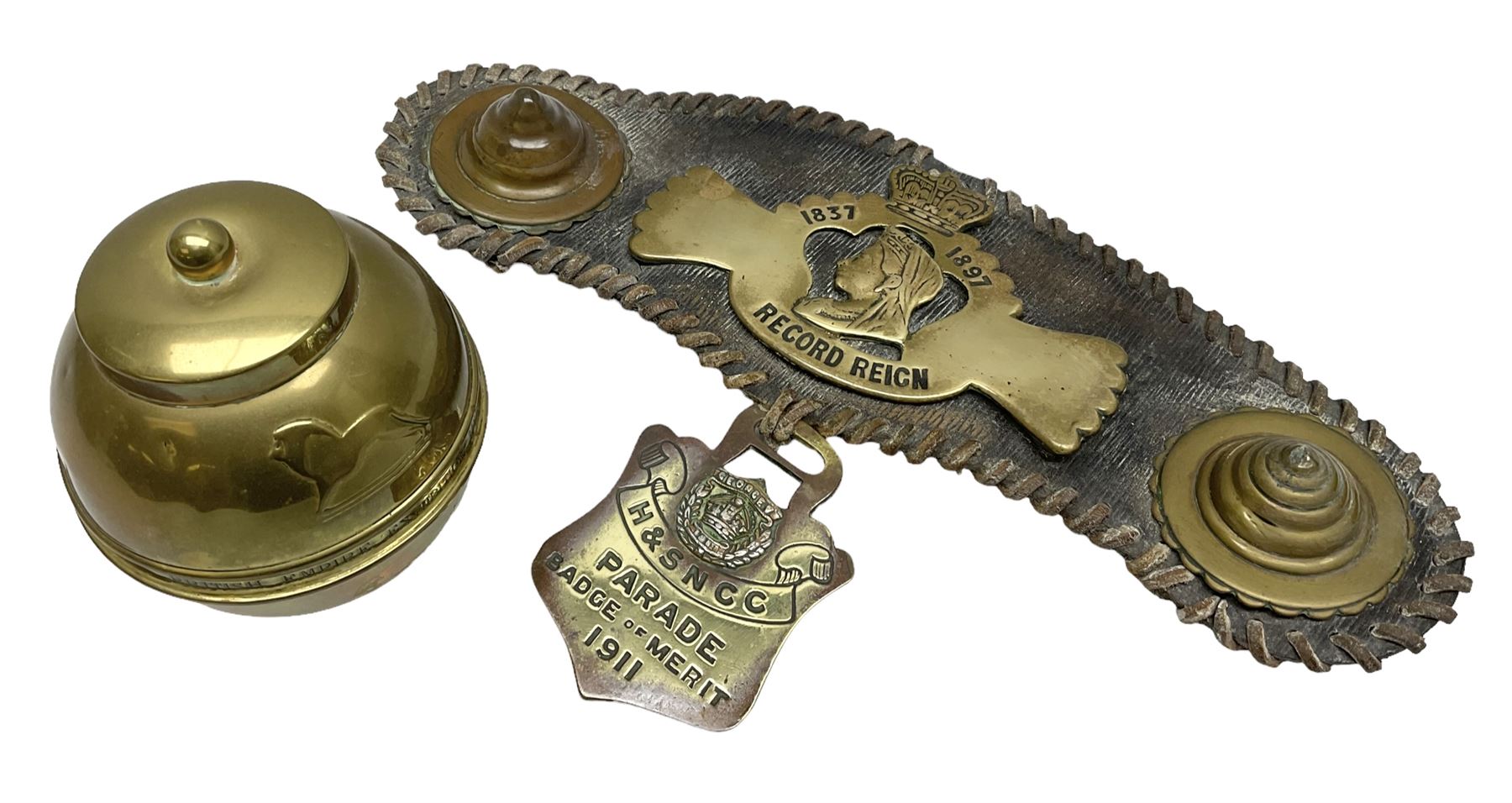 Victorian Queen Victoria record reign horse brass and H&SNCC Parade Badge of Merit 1911 horse brass, both on leather strap, together with 1924 British Empire Exhibition brass Lipton's souvenir tea caddy, strap L36cm