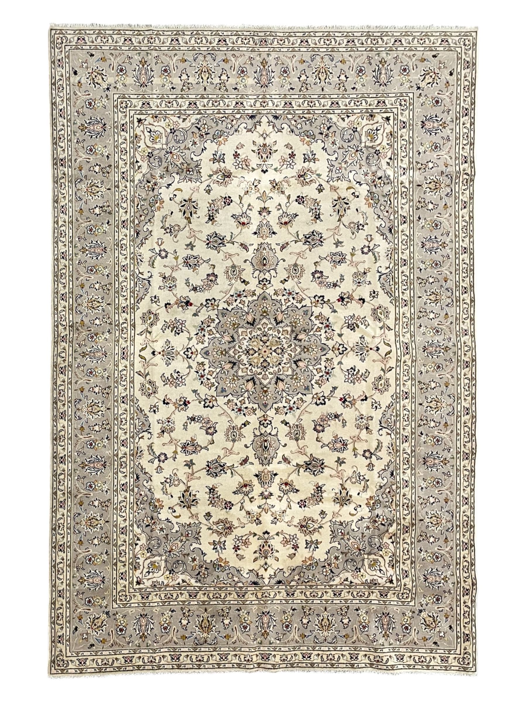 Persian Kashan ivory ground carpet, floral central medallion surrounded by trailing leafy branches and palmettes, floral pattern spandrels and matching border, within guard stripes