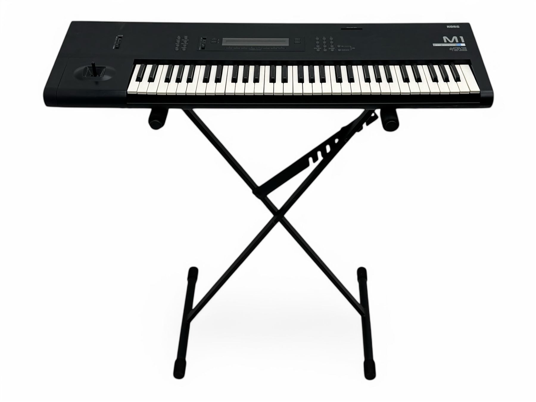 Korg M1 keyboard synthesiser, 61 velocity-sensitive keys with integrated multi-effects and eight-track sequencer, mounted on an adjustable black tubular X-frame stand with rubber end caps