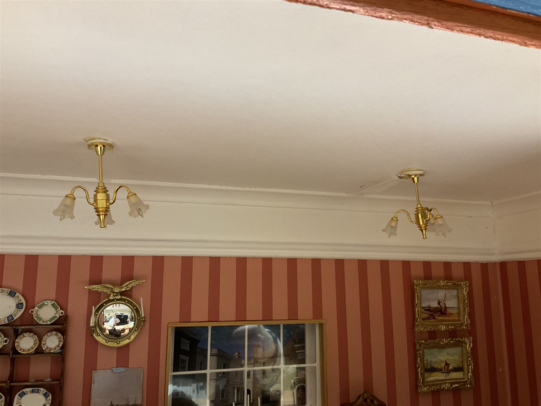 Good quality late 20th century dolls house by M. James dated 1995 in the form of a Beverley East Yorkshire Antique Shop called 'North Bar Antiques'; single-storey single-roomed shop with textured brick walls and flat roof, fully glazed hinged front with recessed hinged customer door and central window to the rear; comprehensively furnished with chests of drawers, pedestal desk, breakfast table, lowboy, two longcase clocks, delft rack with ceramics, occasional tables, pictures, Regency style mirror and collectibles; decorated walls with coving and picture rail and simulated floorboarding; wired for electric lighting; maker's plaque W61cm H42.5cm D41.5cm