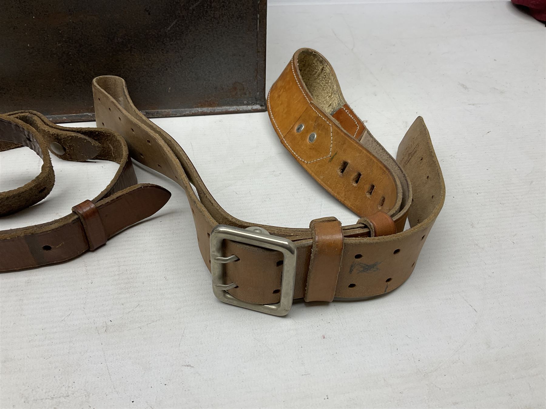 Assorted militaria including ten leather or canvas cartridge and other belts, maroon beret with 17th Lancers cap badge, modern bullet mould, leather and brass shot flask, two knives, shell cases, boomerang etc; in tin deed box