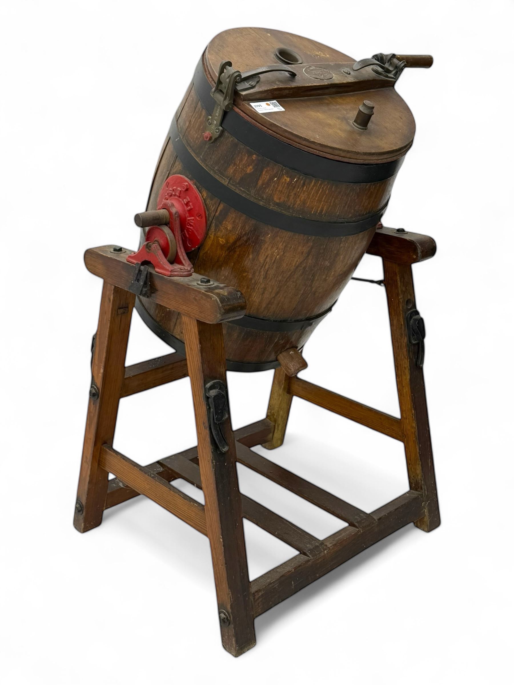 19th century oak and cast iron rotary butter churn, with coopered barrel body, domed lid with filler opening and cast iron securing arms, on tilting iron-mounted frame with crank handle and support rails
