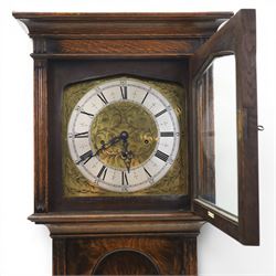Early 20th century oak longcase clock, square brass dial with engraved foliate spandrels and centre, silvered Roman chapter ring with Arabic minute track, Westminster chime movement, the plain case with glazed arched trunk door and moulded plinth