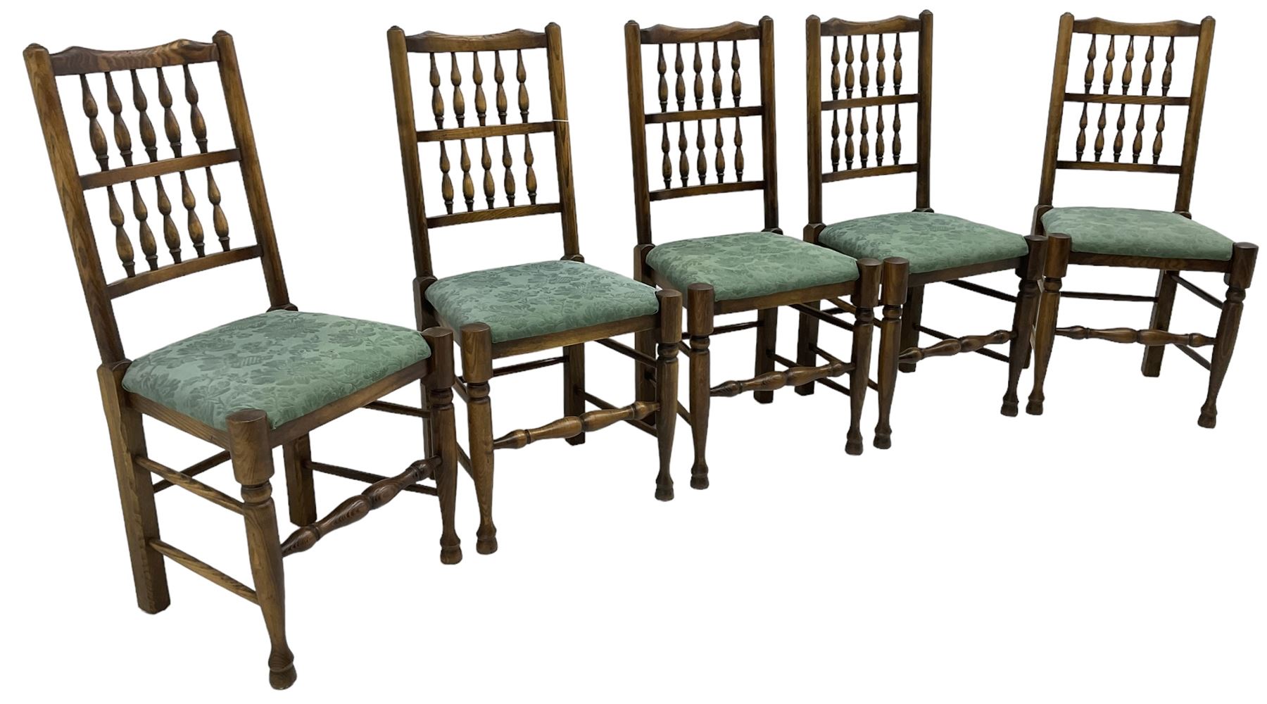 Set of five Lancashire design elm spindle back chairs, shaped cresting rail over two rows of five spindles, upholstered drop-on seats, on turned front supports united by turned stretchers  