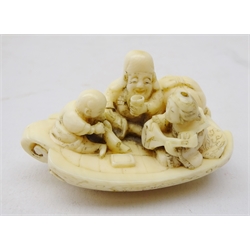  19th century Japanese ivory Netsuke of three figures on a boat reading, drinking and playing the lute, L5cm   
