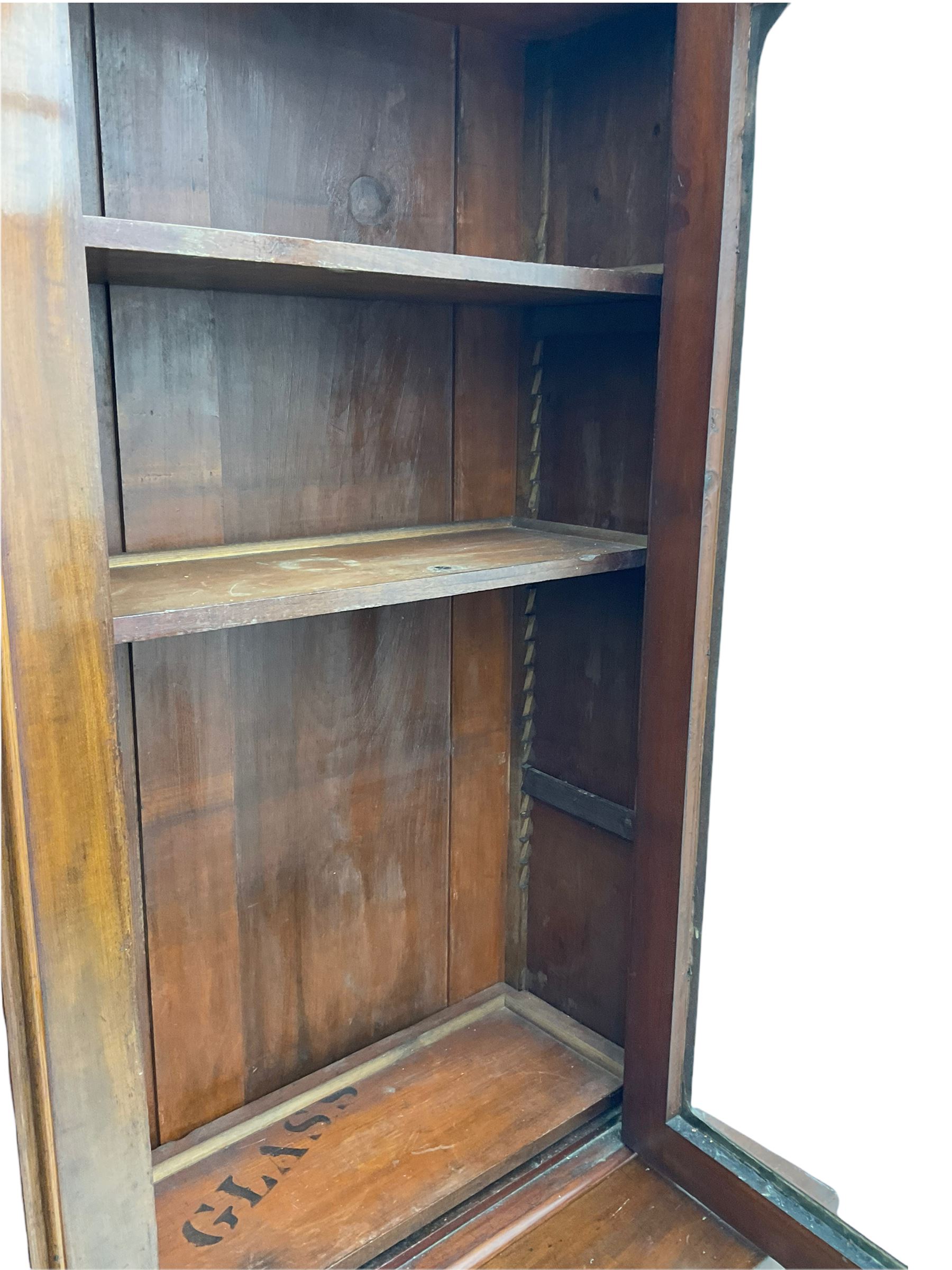 Victorian mahogany bookcase on cupboard, projecting cornice over two glazed doors and carved corbels, fitted with two drawers and double cupboard, plinth base