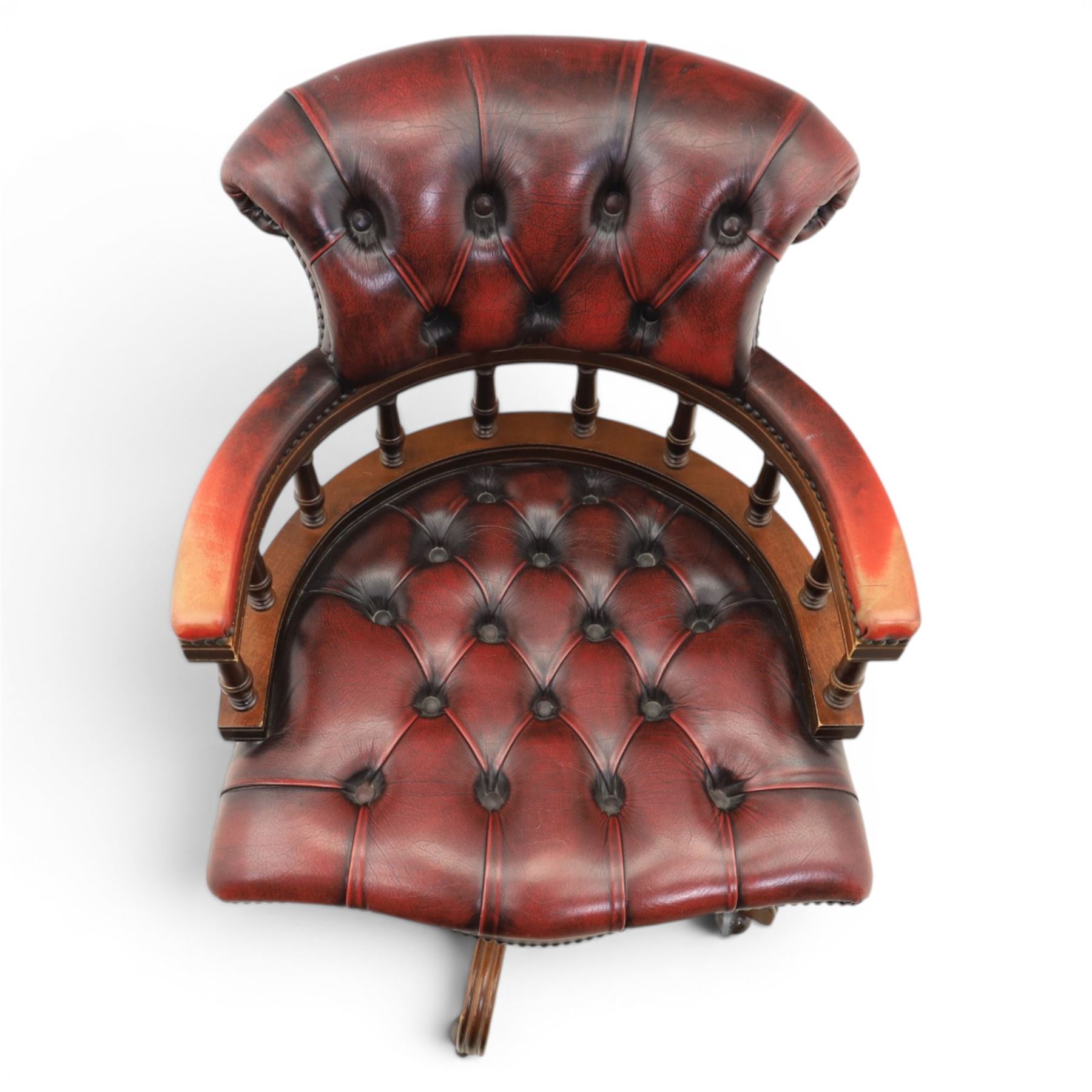 Captains swivel desk chair upholstered in oxblood leather, buttoned back and seat, shaped arm bow raised on turned spindles, five spoke base raised on castors