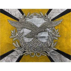 Two replica German Luftwaffe trumpet banners, one heavily silver wire embroidered with Luftwaffe eagle in a wreath, on an amber, white and black rayed background, , with silver wire tasselled border and four leather hanging loops, approx. 50 x 49cm; the other slightly larger heavily gold wire embroidered with the Luftwaffe eagle on a plain amber ground with gold wire tasselled border and two hanging loops (2)