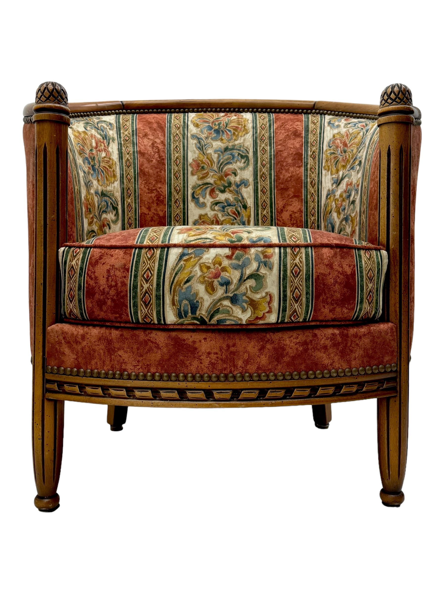 Pair of cherry wood framed tub-shaped armchairs, upholstered in striped floral fabric with brass stud trim, carved walnut frame with fluted supports capped with pinecone finials, on turned feet